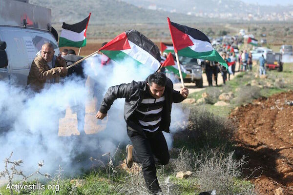Palestinian protesters flee tear gas at a non-violent protest in which Palestinian Minster Ziad Abu Eid died. Activists set out to plant olive trees on lands usurped by Israeli settlements, December 10, 2014. (Photo by Oren Ziv/Activestills.org)