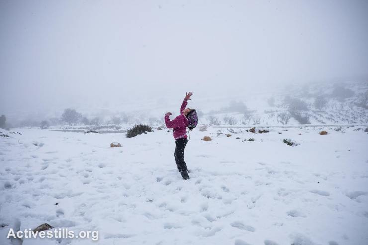 A Palestinian girl plays during a snow storm, West Bank, on January 10, 2015. (photo: Activestills.org)