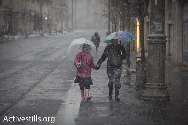 A couple walks during a snowstorm in Jerusalem, January 7, 2015. (photo: Oren Ziv/Activestills.org)