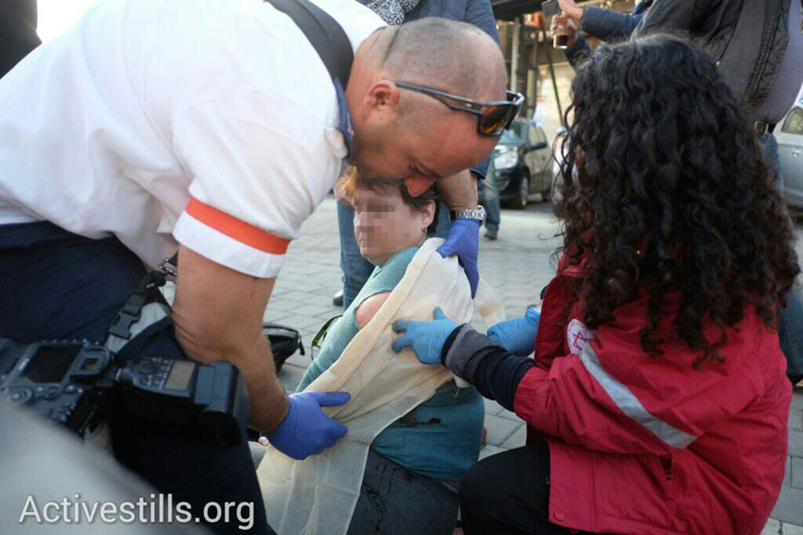 Medics treat a victim of a stabbing attack on a Tel Aviv bus line, January 21, 2015. (Activestills.org)