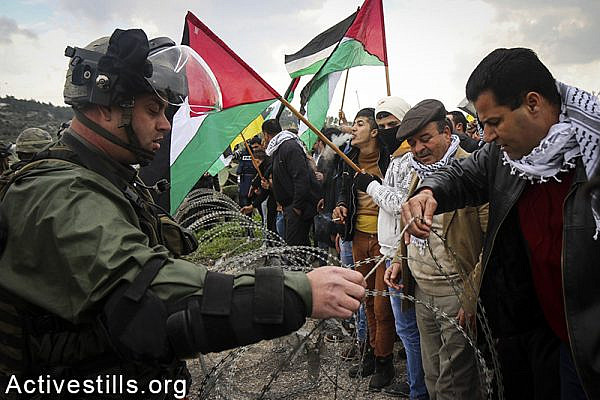 Palestinians from the West Bank village of Azzun protesting near Israeli soldiers for the opening of the eastern gate to the village, which has been closed by Israel since 1990, February 14, 2015. Ahmad al-Bazz / Activestills.org