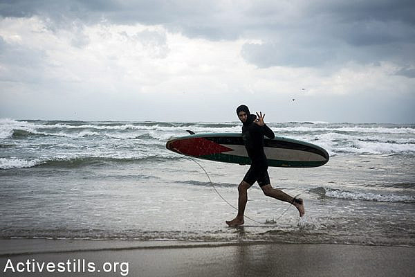 A youth runs to the water with his surfboard, Gaza beach, February 12, 2015. Anne Paq / Activestills.org
