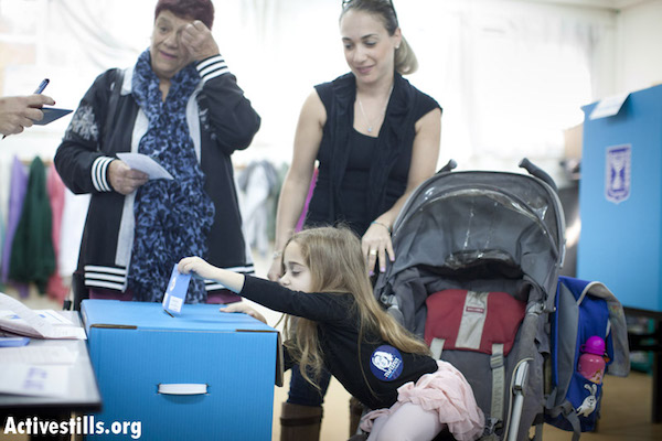 A small Israeli girl casts her mother's vote in the 2013 Knesset elections. (photo: Yotam Ronen / Activestills)