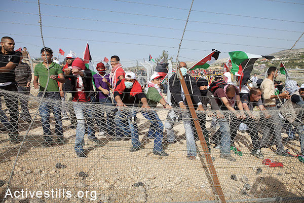 Demonstrators dismantle a section of the wall during a demonstration marking the fifth anniversary of the struggle against the Israeli separation barrier in the West Bank village of Bil'in, Friday, 19, 2010. By: Anne Paq / Activestills.org