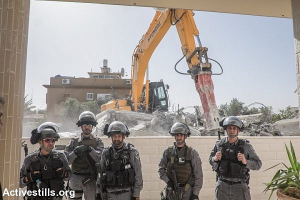 Israeli police officers stand guard as the home of Hana al-Nakib and her four children is demolished, in the city of Lod, February 10, 2015.  (Yotam Ronen/Activestills.org)
