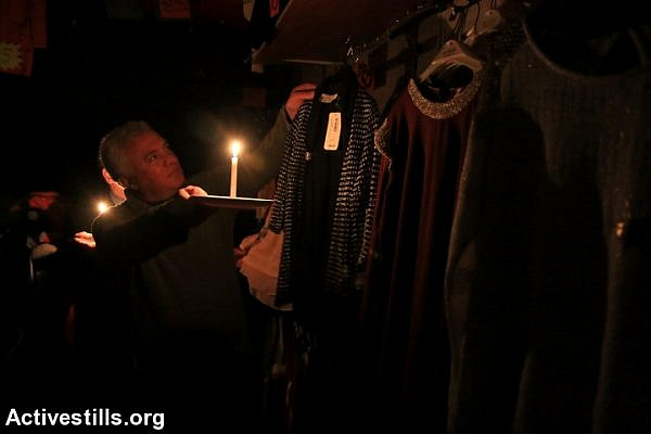 A vendor in Nablus uses a candle in his store, after Israel Electric Company deliberately shut down power to the city and the surrounding area. (photo: Ahmad al-Bazz/Activestills.org)