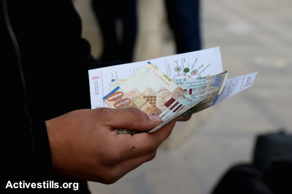 A Palestinian public-sector worker holds part of his salary withdrawn from an ATM, Nablus, West Bank, February 9, 2015. (photo: Ahmad Al-Bazz/Activestills.org)
