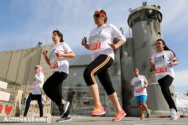 Runners pass the Israeli Separation Wall dividing the West Bank city of Bethlehem in the third annual Palestine Marathon, March 27, 2015. Some 3,200 Palestinian and international runners participated in 10K, half marathon and full marathon races under the title “Right to Movement”. Full marathon runners had to complete two laps of the same route, as organizers were unable to find a single course of 42 uninterrupted kilometers under Palestinian Authority control in the area.