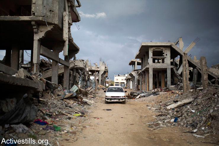 Palestinians drive through a destroyed quarter of Al Shaaf neighborhood, in Al Tuffah, east of Gaza City, March 21, 2015.