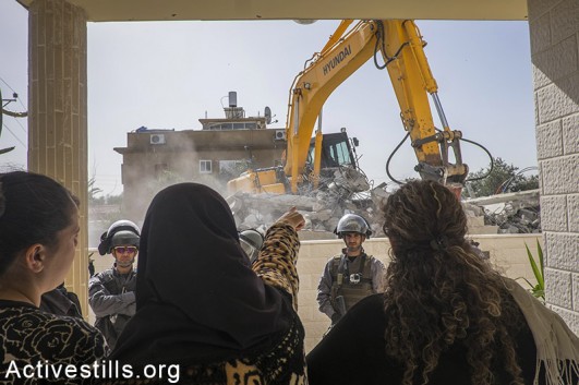 Israeli police officers stand guard as the home of Hana al-Nakib and her four children is being demolished, in the city of Lod, February 10, 2015. The house was built with the help of family members and neighbours who donated money to help the single mother. The house was built on a family-owned land, but without permission from the Israeli authorities. Palestinian citizens of Israel can hardly attain building permits due to Israel's discriminative criterions. Oren Ziv / Activestills.org