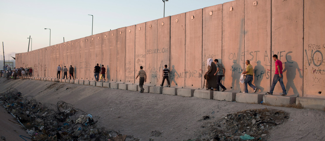 Palestinians walk along the separation wall in the West Bank. (Activestills.org)