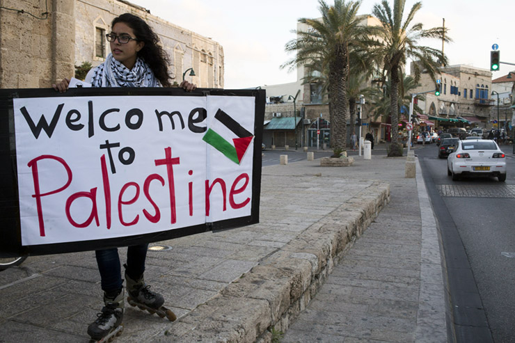 A young woman holds a sign at a demonstration commemorating Land Day in Jaffa, March 30, 2014. Land Day marks the deaths of six Palestinians protesters at the hands of Israeli police and troops during mass demonstrations on March 30, 1976, against plans to confiscate Arab land in Galilee. (Activestills.org)