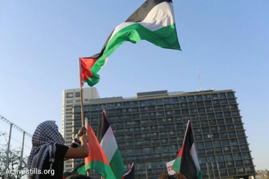 Palestinian flags wave in front of Tel Aviv City Hall at a demonstration against the government's housing discrimination and policy of home demolitions, Rabin Square, Tel Aviv, April 28, 2015. (Oren Ziv/Activestills.org)