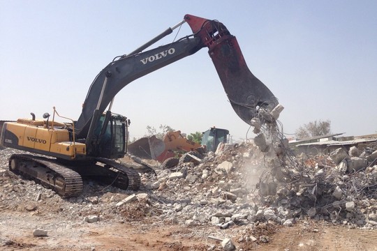 A bulldozer demolishes an apartment building in the unrecognized village Dahmash, April 15, 2015. (photo: Rami Younis)