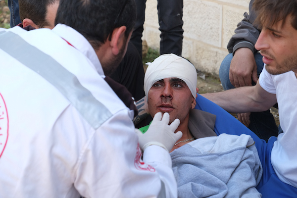 A medic treats a Palestinian man who was apparently shot in the head by IDF soldiers, Nabi Saleh, April 24, 2015. (Miki Kratsman/Activestills.org)