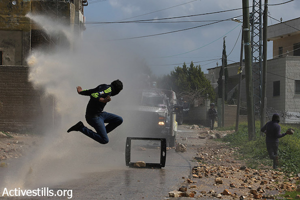 A Palestinian youth jumps to avoid a water canon during clashes with the Israeli army at the weekly protest against the occupation, Kafr Qaddum, West Bank, March 13, 2015. Locals began to organize demonstrations in July 2011 to protest the blocking of the main road linking Kafr Qaddum to Nablus. (photo: Activestills.org)