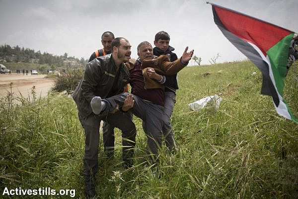 Protesters carry a Palestinian man who was injured during a protest marking Palestinian Prisoners' day, outside Ofer military prison, near the West Bank town of Betunia, April 16, 2015. (photo: Oren Ziv/Activestills.org)