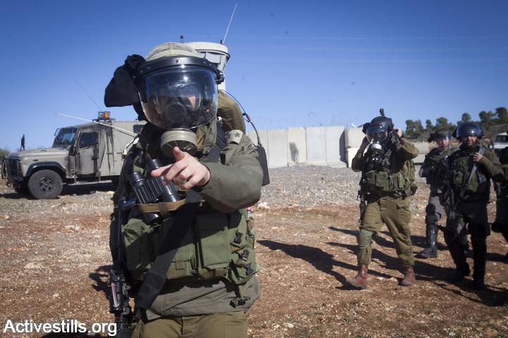 An Israeli soldier warns photographers during clashes following the funeral of Mustafa Tamimi in the West Bank village of Nabi Saleh, December 11, 2011. (photo: Oren Ziv/Activestills.org)