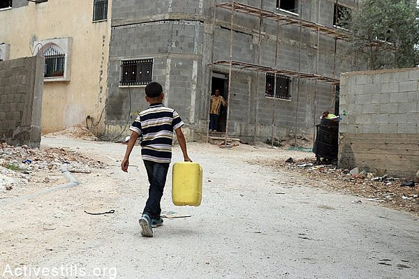 Palestinian child carries water gallon in Qarawat Bani Hassan village, West Bank, May 23, 2015. According to the municipal council of Qarawat Bani Hassan the portion of a each villager has decreased to two litters per day as the village receive only 97 Cubic meter per hour. The municipal council said the Israeli authorities did not provide the village with answers regarding the situation. Ahmad al-Bazz / Activestills.org