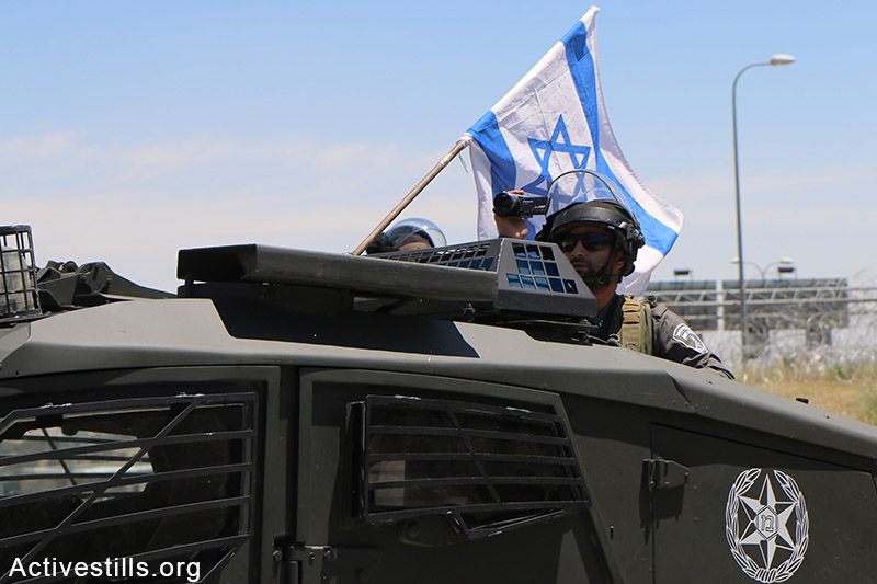 Israeli soldier films as Palestinians from the West Bank village of Al Zaeem call for the opening of the Separation Wall gate that leads from Jerusalem to the village, May 8, 2015. The gate is held closed by Israeli authorities for over two weeks. Ahmad al-Bazz / Activestills.org