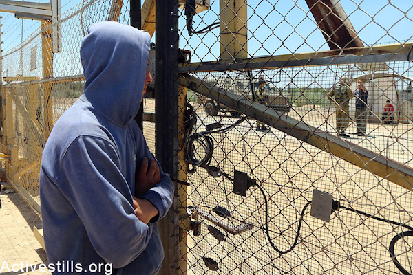 A Palestinian farmer stands beside an agricultural gate in the separation fence near Falamya village (Gate number 914), West Bank, May 17, 2015. Ahmad al-Bazz / Activestills.org