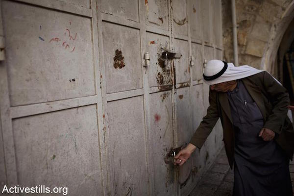 A Palestinian shopkeeper locks his store to prevent it from being attacked, shortly before Israeli nationalists enter the area in the “March of the Flags", Damascus Gate, East Jerusalem, May 20, 2012. (Oren Ziv/Activestills.org)