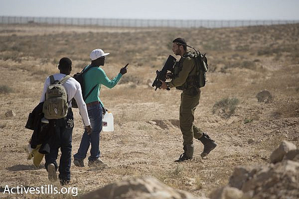 An Israeli soldier stops asylum seekers from approaching the Egyptian border.
