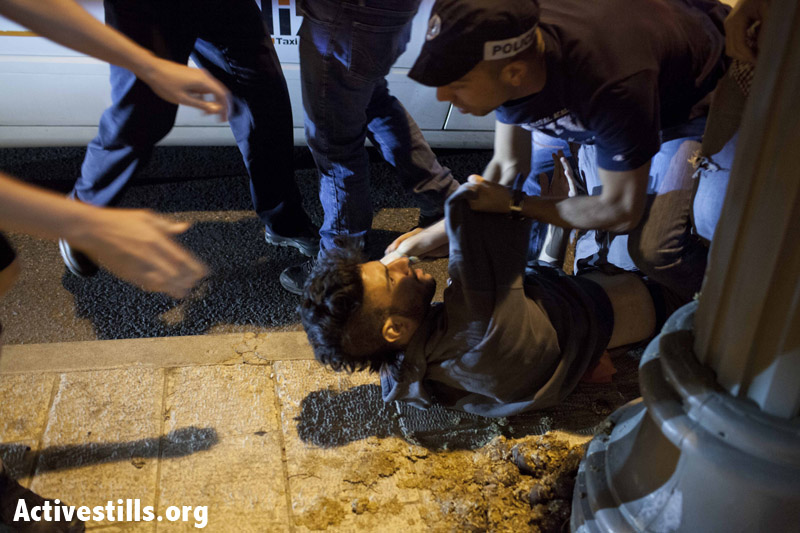 An activist arrested by an Israeli policeman, at a road blockset up in the center of West Jerusalem as part of a protest against the Israeli government's decision to privatize and export natural gas found in the Mediterranean sea,June 22, 2013. Nine activists were arrested during the demonstration. (Tali Mayer/Activestills.org) 