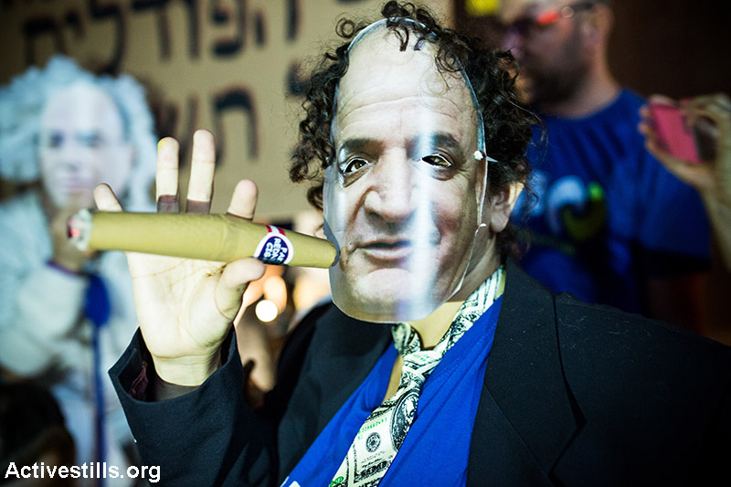 Protester wearing a mask of business man Ytzhak Tshuva owner of an energy company  during a protest against natural gas privatisation in Tel Aviv, June 27, 2015. Around 4000 people marched in the demonstration. (Yotam Ronen/Activestills.org)