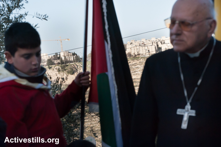 With the Israeli settlement Gilo visible on a nearby hillside, Latin Patriarch Emeritus Michel Sabbah joins Palestinians in a prayer service as a nonviolent witness against the Israeli separation barrier in the West Bank town of Beit Jala, February 8, 2013. All Israeli settlements are illegal under international law. (photo: Ryan Rodrick Beiler/Activestills.org)