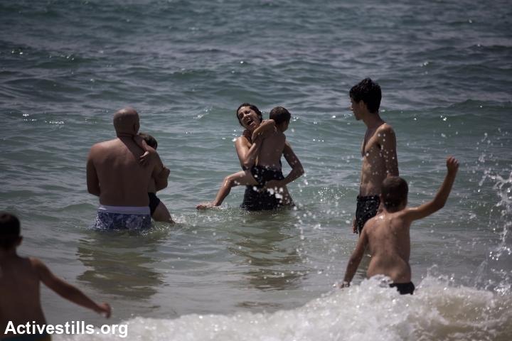Israeli and Palestinian activists play in the water with Palestinian kids from the West Bank village of Nabi Saleh, at the beach in Jaffa during the holy month of Ramadan, August 4, 2013.  (photo: Oren Ziv/Activestills.org)