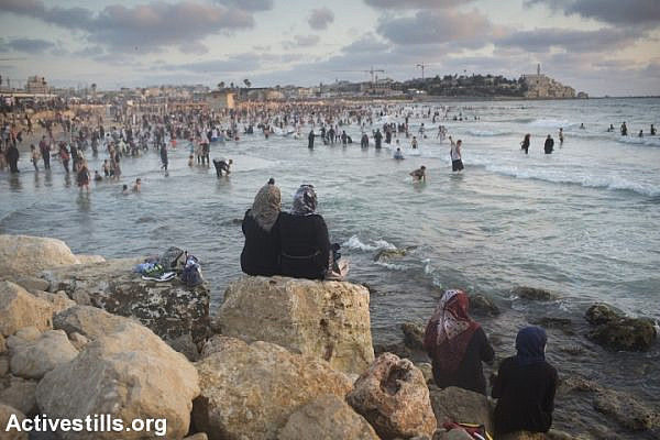 Palestinians, many of whom came from the West Bank, sit near the Mediterranean Sea during the last day of the Eid al-Fitr holiday as the sun sets in Jaffa, July 19, 2015.