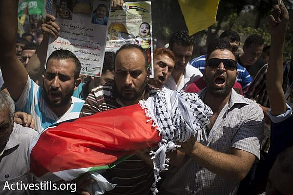 Palestinians in the West Bank village of Duma carry the body of 18-month-old Ali Saad Dawabshe after he was slain in an arson attack during the early hours of the morning, July 31, 2015. (Oren Ziv/Activestills.org)