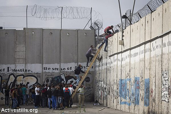 Palestinians climb over the Israeli Wall to attend the Friday prayer in Al-Aqsa Mosque, in the town of Al-Ram, near the Qalandiya checkpoint between the West Bank city of Ramallah and Jerusalem, on the second Friday of the Muslim holy month of Ramadan, June 26, 2015. (Activestills.org)
