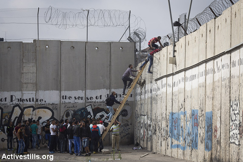 Palestinians climb over the Israeli Wall to attend the Friday prayer in Al-Aqsa Mosque, in the town of Al-Ram, near the Qalandiya checkpoint between the West Bank city of Ramallah and Jerusalem, on the second Friday of the Muslim holy month of Ramadan, June 26, 2015. (Activestills.org)