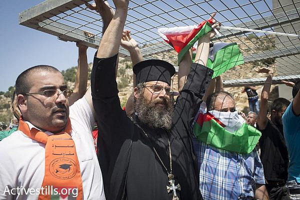 Father Paolo from Beit Jala's Catholic church carries a piece of a checkpoint, during a Muslim-Christian protest against the planned route of the separation barrier, Beit Jala, West Bank, August 23, 2015. (photo: Oren Ziv/Activestills.org)