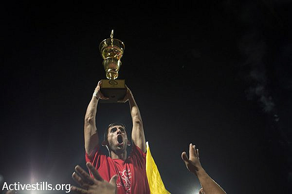 Al Ahly fans and team players celebrate after a football match for the Palestine Cup final between Gaza's Shejaia's club and Hebron's Al-Ahly club on August 14, 2015 at Hussein Bin Ali Stadium in the West Bank city of Hebron. Hebron's Al-Ahly won 2-1, in the first footballing showdown in 15 years with a team from Israeli-blockaded Gaza to be proclaimed Palestinian champions. Al-Ahly will now represent Palestine, a member of football's world governing body FIFA since 1998, in international competitions. (Oren Ziv / Activestills.org)