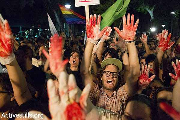 Israeli protesters wave red-painted hands and calling against racist and homophobic propaganda disseminated by Israeli government officials and members of Knesset during their speeches in protest against racism and homophobia, Tel Aviv, Israel, August 1, 2015. Protests were held tonight in Tel Aviv, Jerusalem, Haifa, Beer Sheva and Gan Shmuel Junction, following recent deadly attacks on the Dawabsha family and the stabbing attack in annual Jerusalem Pride Parade. (Activestills.org)