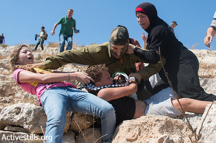 Members of the Tamimi family prevent from an Israeli solider from arresting Mohammed Tamimi, 11, during the weekly protest against the occupation in the West Bank village of Nabi Saleh, August 28, 2015. (photo: Muhannad Saleem / Activestills.org)
