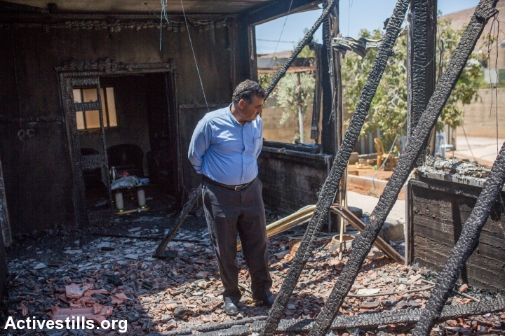 A man examines the burnt house of the Dawabsha family during the funeral procession of Saad Dawabsha, in the West Bank village of Duma, August 8, 2015. (photo: Yotam Ronen/Activestills.org)