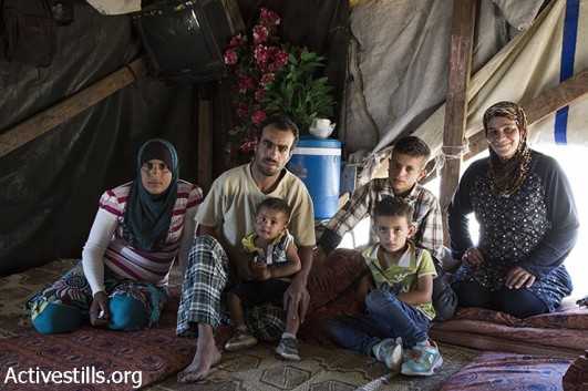 The Nawaja family sits in their tent that is slated for demolition by Israeli authorities, Susya, south Hebron Hills, West Bank, July 3, 2015. (Keren Manor / Activestills.org)