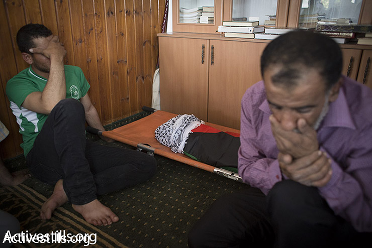 Relatives of 18-month-old Palestinian boy Ali Dawabshe, who was killed along with his mother and father when Jewish terrorists set their home on fire, mourn next to his body during his funeral in the West Bank village of Duma, July 31, 2015. (Oren Ziv / Activestills.org)