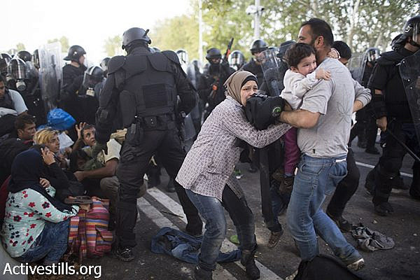 Hungarian policemen attack refugees during a protest in front a closed gate on the Serbian side of the Serbian-Hungarian border, September 16, 2015.