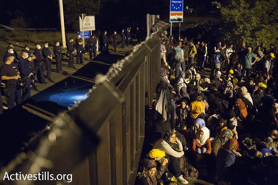 Refugees sit in front of the police checkpoint at the Serbia-Hungary border crossing, September 15, 2015. (photo: Oren Ziv/Activestills.org)