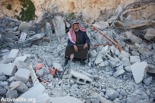 A member of the Jahalin Bedouin sits on the remains of his demolished home in Al Eizariya, West Bank, March 18, 2009. (photo: Anne Paq)