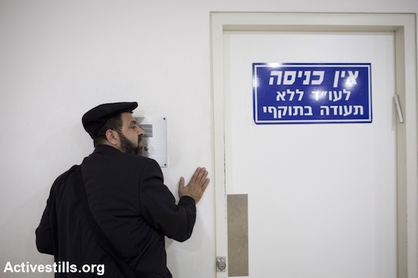 Hassan Jabareen, wearing his trademark hat, waits to see a client in Haifa court, October 16, 2013. (Oren Ziv/Activestills.org)
