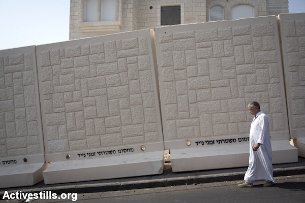 A Palestinian man walks past a newly erected temporary concrete wall that  in the East Jerusalem neighborhood of Jabel Mukaber October 19, 2015. (Oren Ziv/Activestills.org)