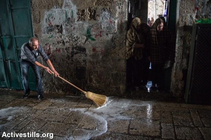 A Palestinian man cleans the scene where a Palestinian woman allegedly tried to stabbed an Israeli man, following which she was shot to death, Jerusalem's Old City, October 7, 2015. (photo: Faiz Abu Rmeleh)