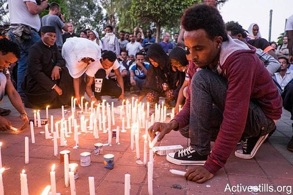 Members of the Eritrean community in Israel light candles at a memorial service for a memorial ceremony for asylum seeker Habtom Zarhum in Levinsky park in south Tel Aviv, October 21, 2015. (Oren Ziv/Activestills.org)
