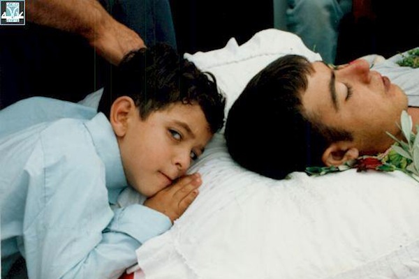 A child lays his head next to one of the Palestinians killed by Israeli police in early October 2000. (Photo courtesy of Adalah.)